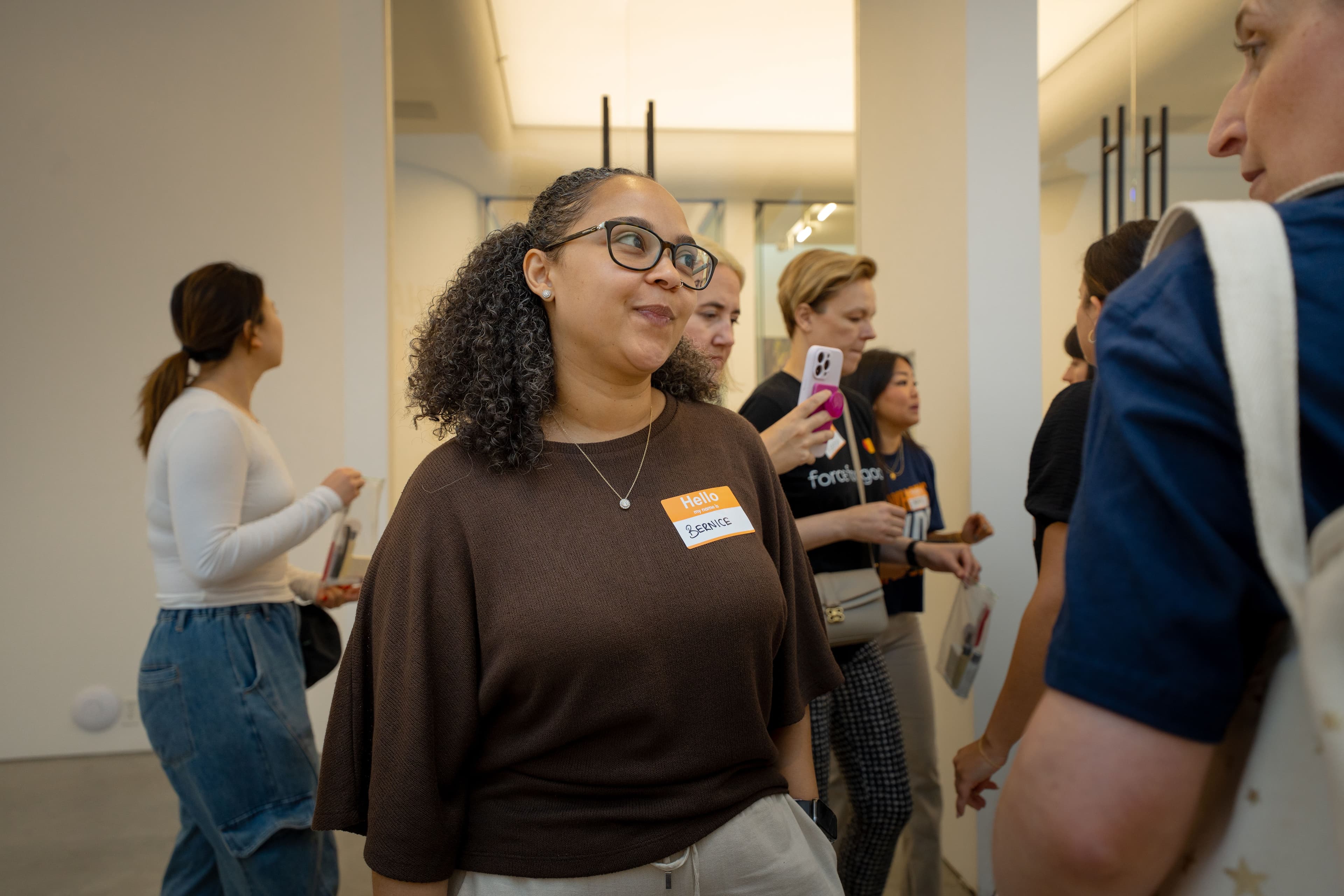 A woman wearing a name tag smiling among other attendees inside the CARE pop-up space